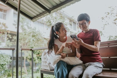 Two people sitting together looking at a phone.