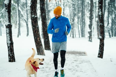 man with his dog jogging on winter day