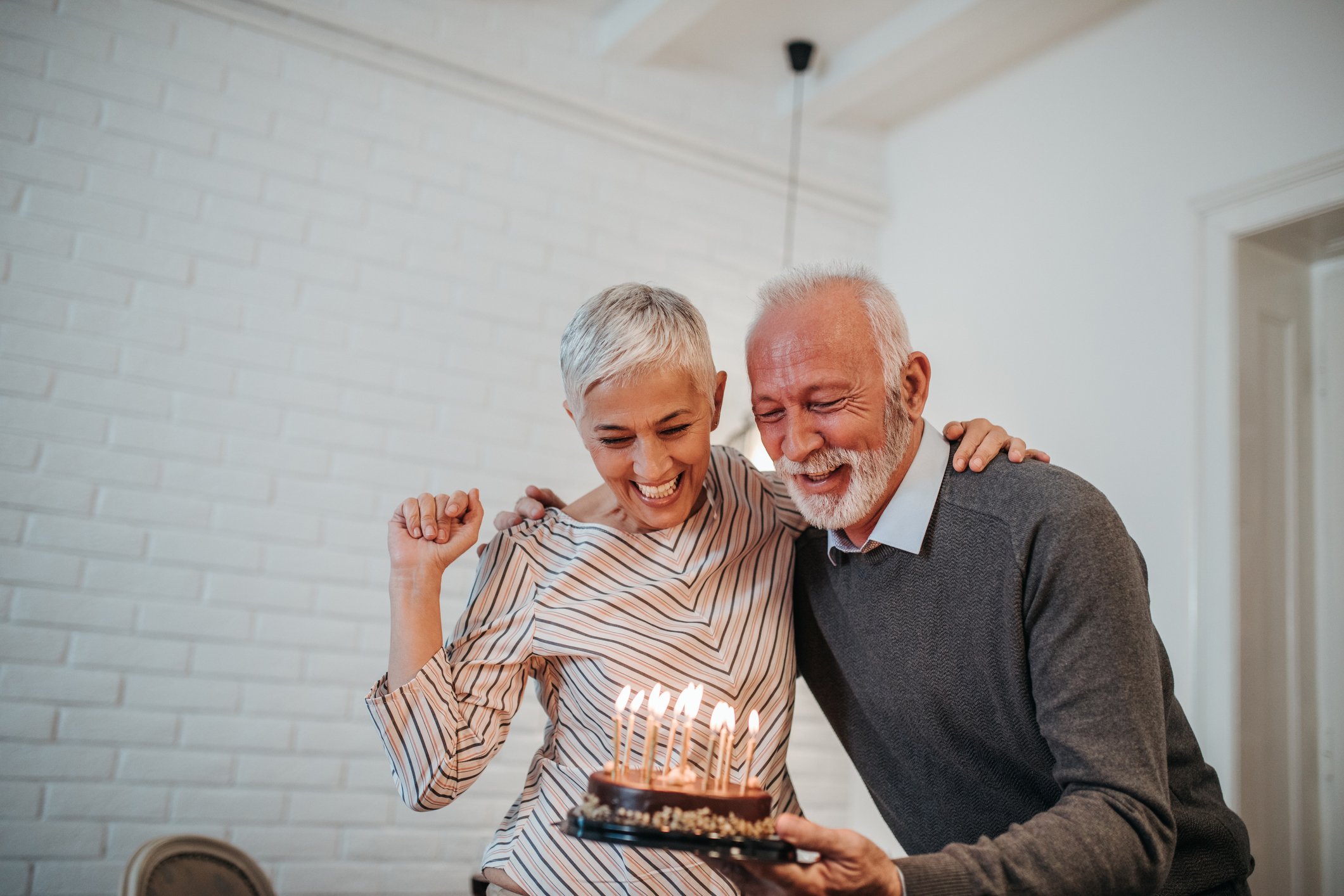 Two people with a cake with lit candles.