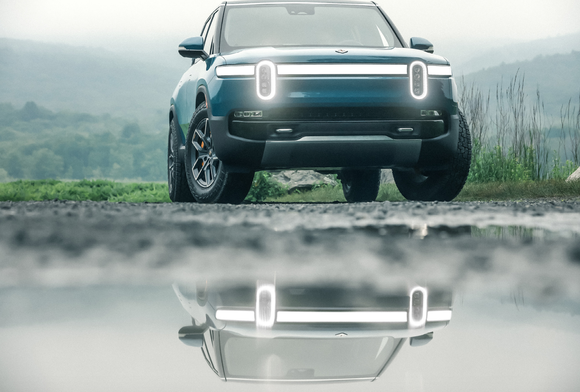 Rivian electric truck reflected in puddle. 
