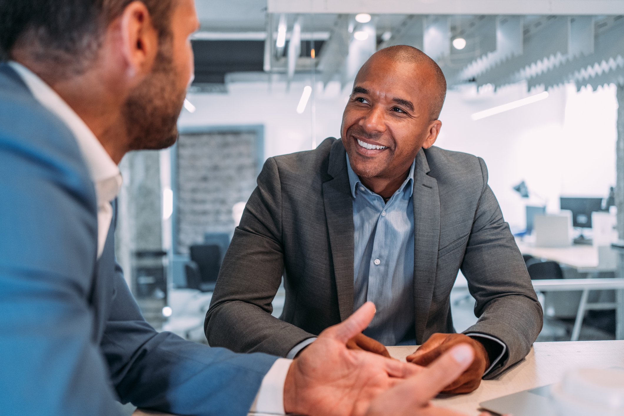 Two business people conversing at a desk. 