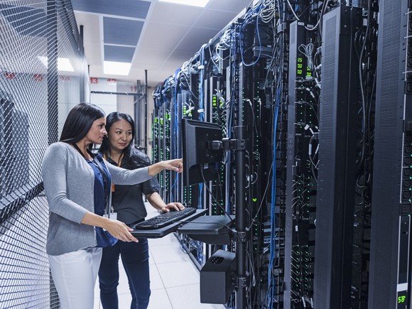 Two people examine network servers.