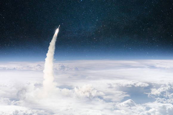 A rocket bursts through the clouds into space. 