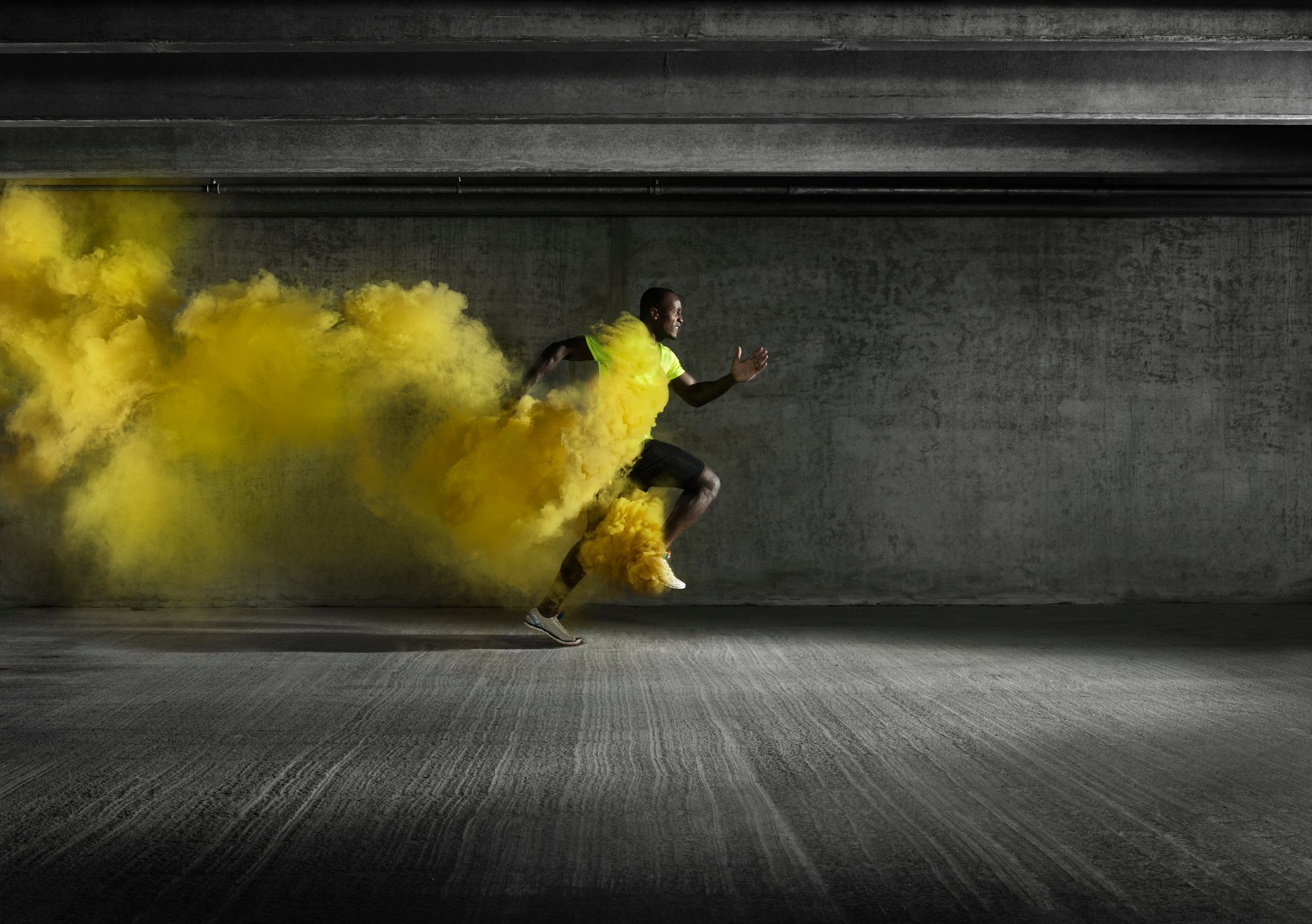A sprinter running fast, leaving behind yellow smoke.
