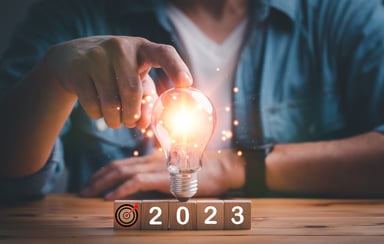 2023 person touching light bulb on wood cube