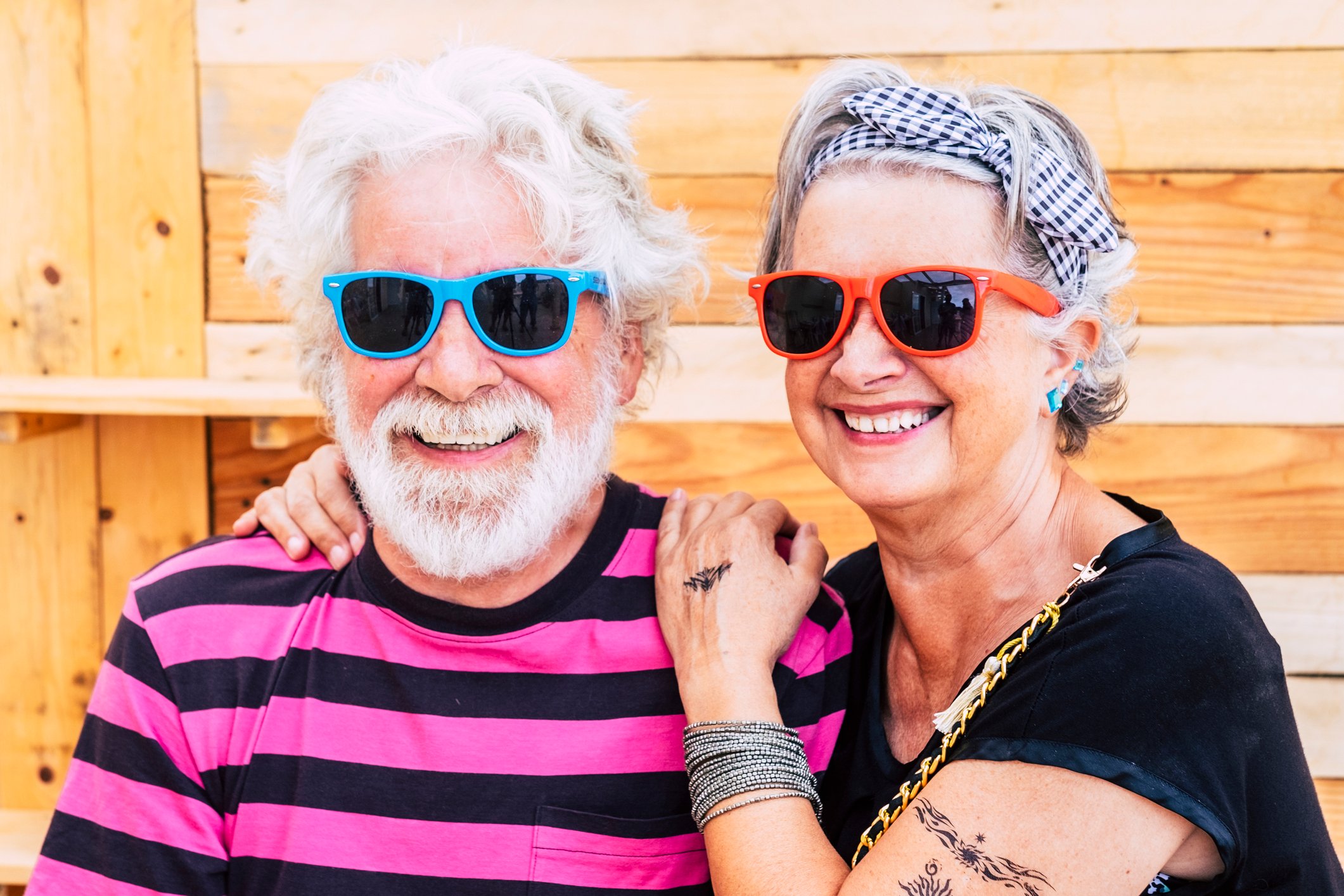 A couple wearing sunglasses smiling together.