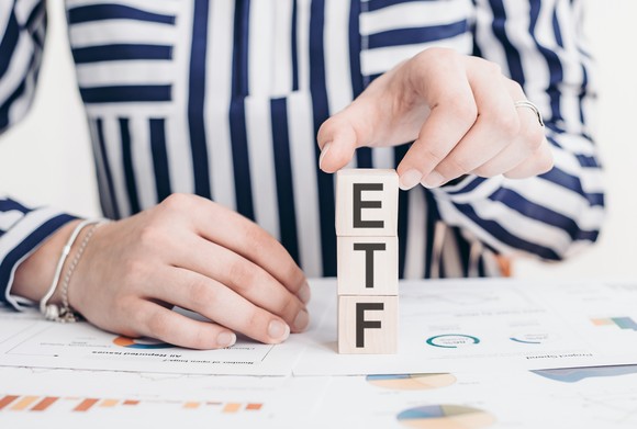 A person stacking blocks that spell "ETF".