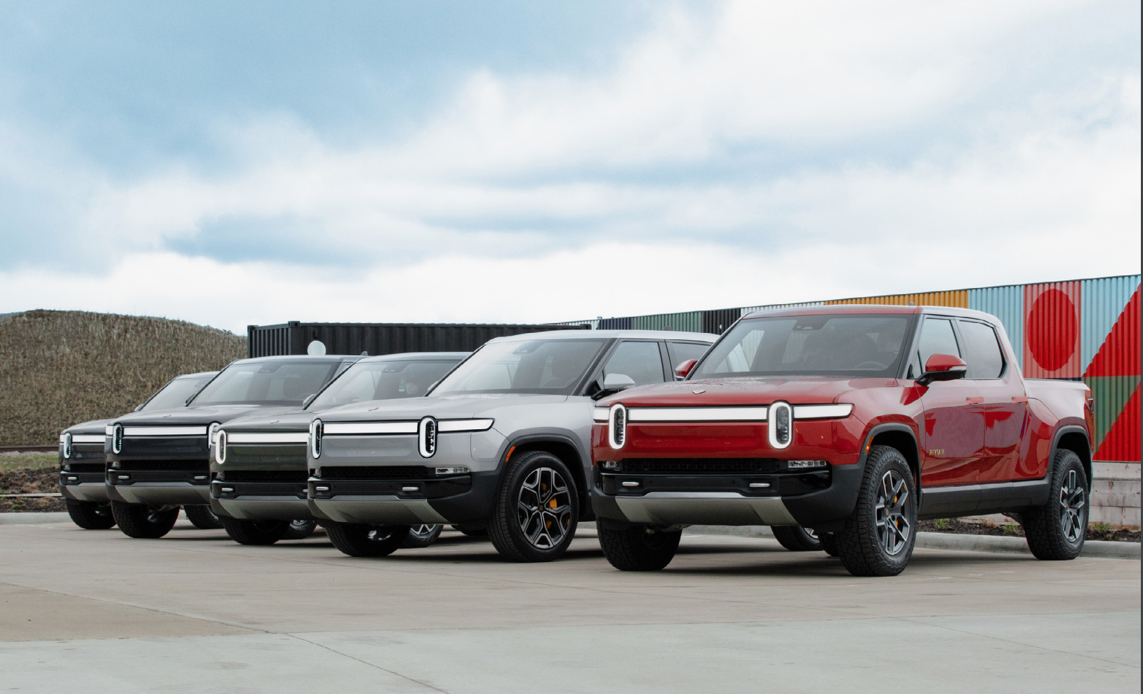 Row of Rivian electric trucks on an outdoor lot.