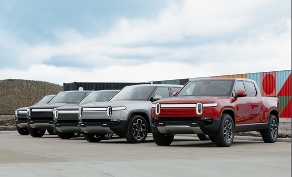 Row of Rivian electric trucks on an outdoor lot.