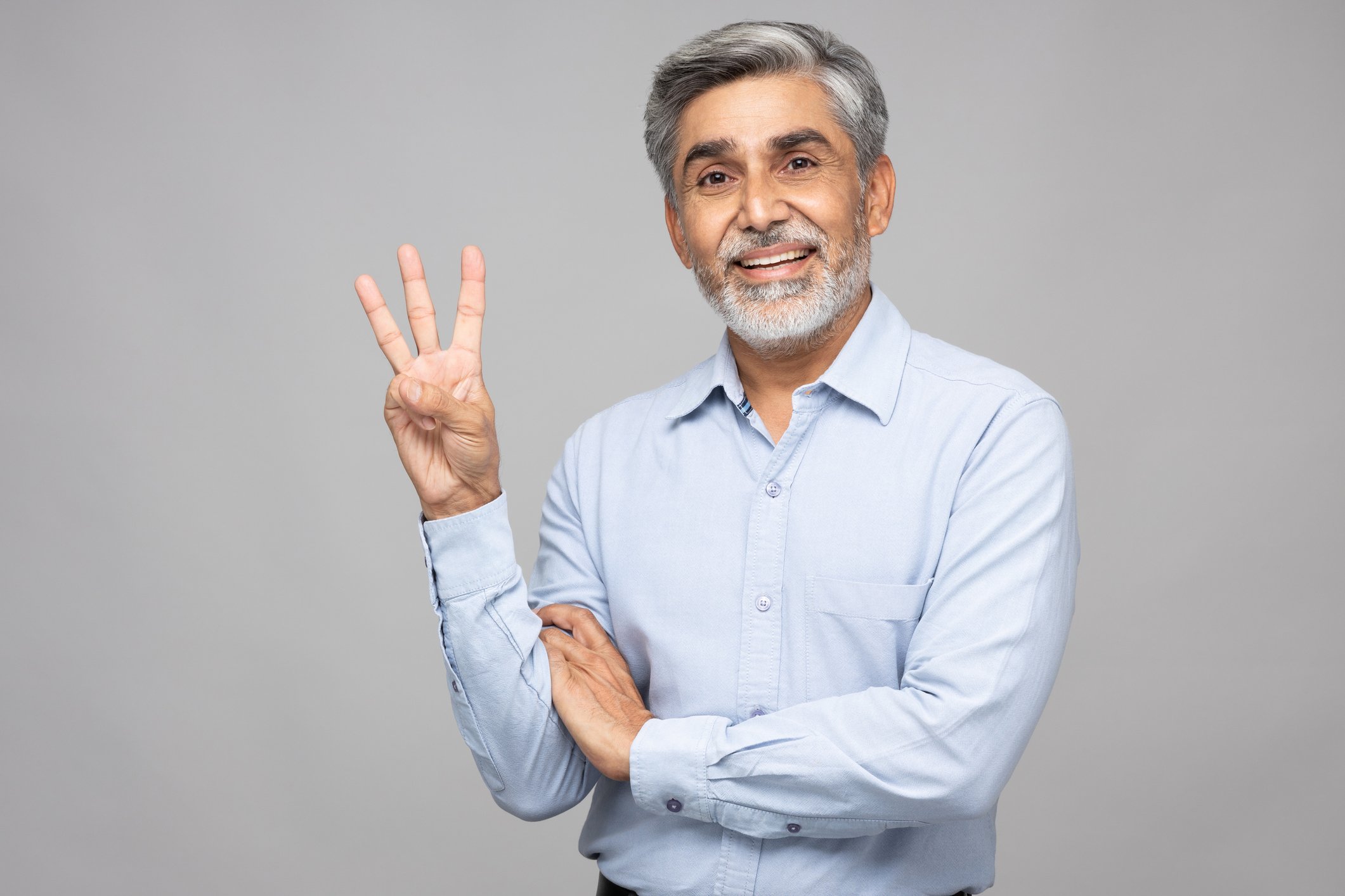 Someone is smiling and holding up three fingers.
