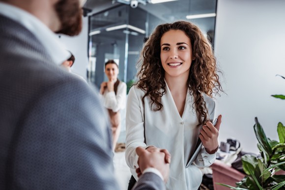 A fashionably-dressed businesswoman meeting a colleague. 