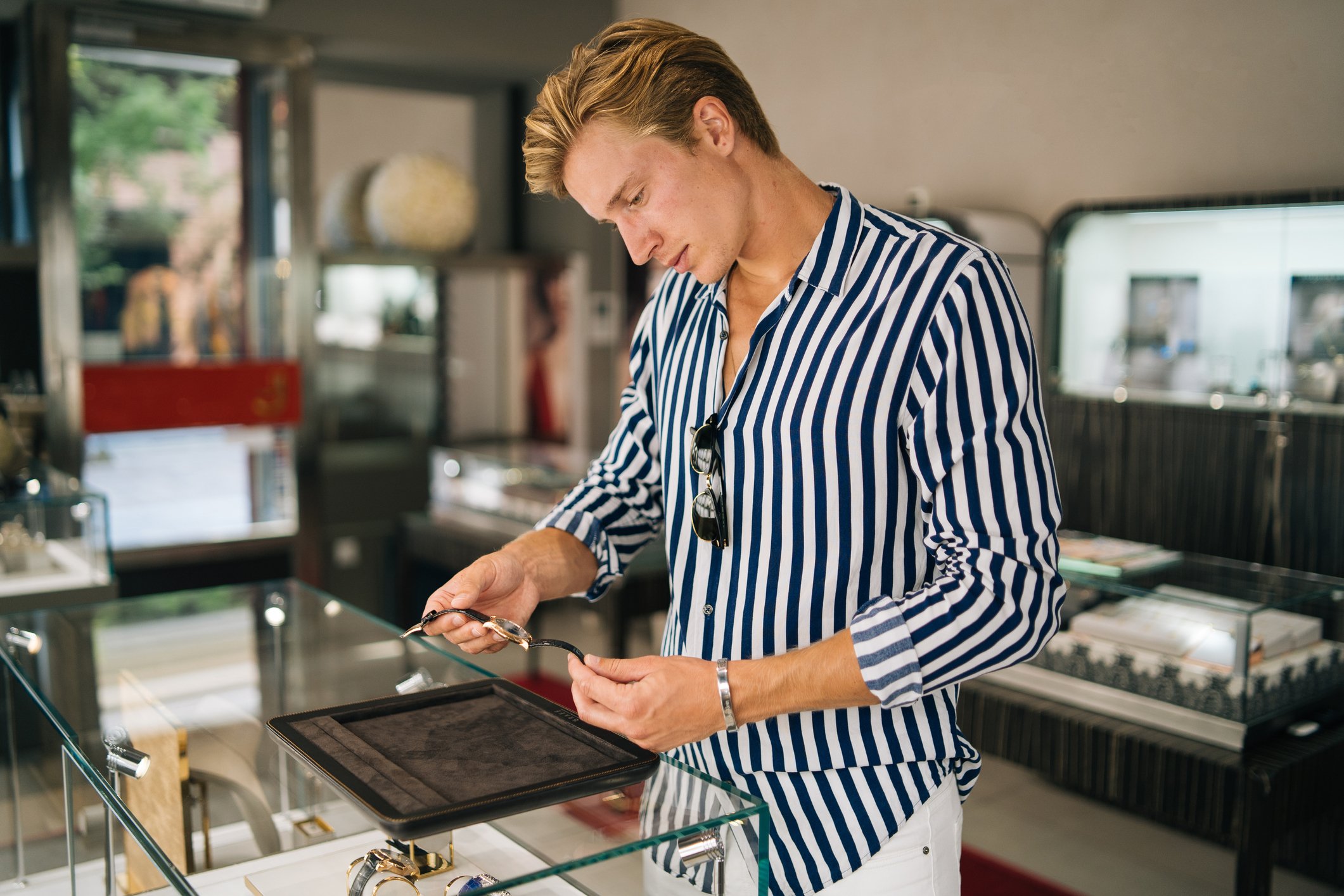 well-coiffed dude looking at watch in a shop