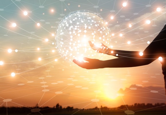 A silhouette of a person holding a sphere of light emitting rays with points in all directions. 