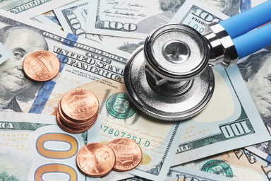Stethescope atop US currency and coins