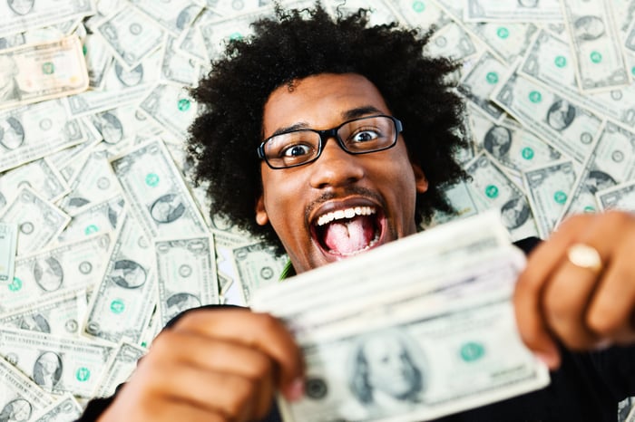 Smiling person laying on pile of cash.