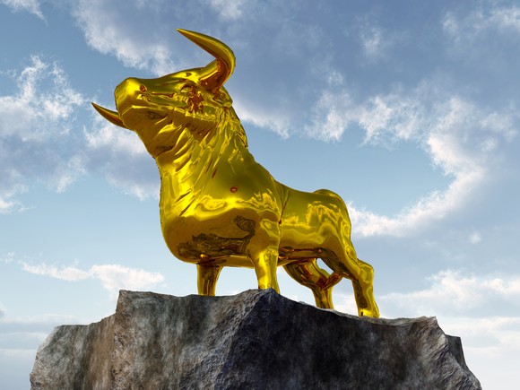 A golden bull statue on top of a cliff.