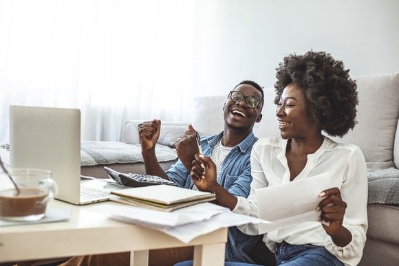 Two people with laptop reviewing documents.