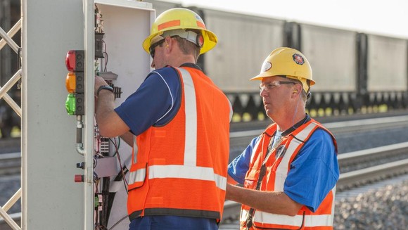 Two workers fixing a railroad signal.