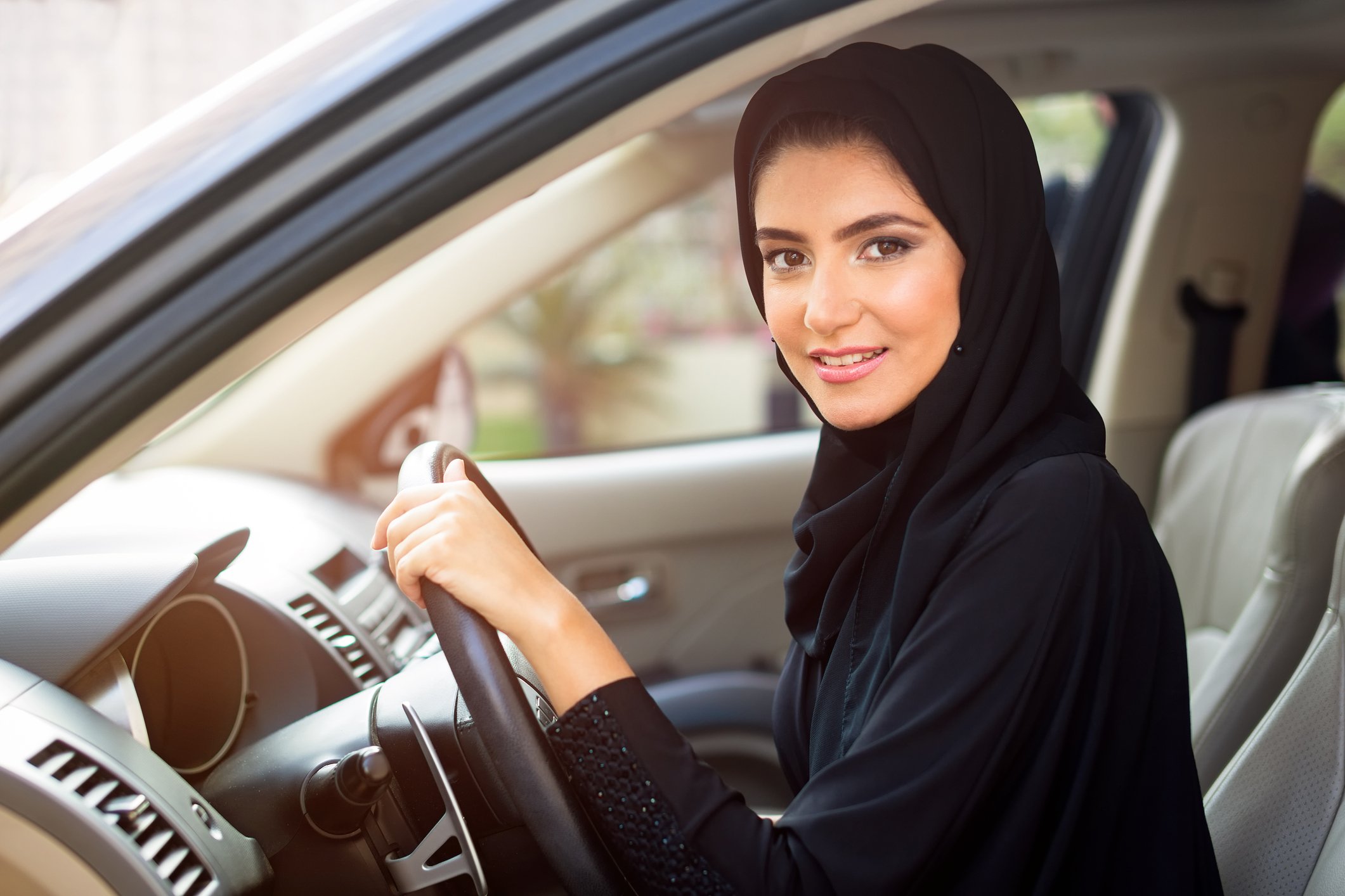 A woman with one hand on the steering wheel of a car.