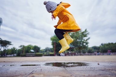 kid jumping in rain puddles