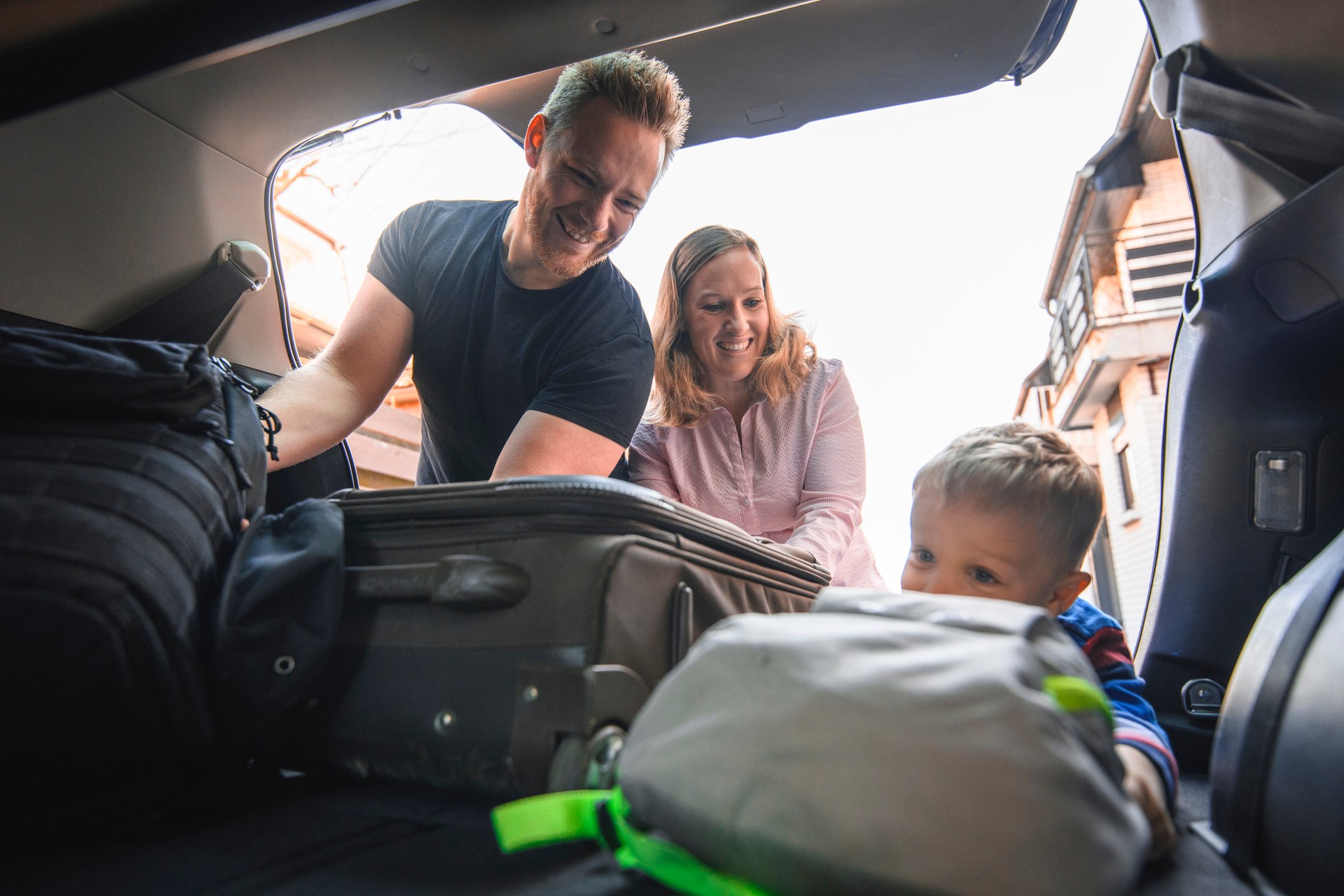 Family packing luggage in a car.