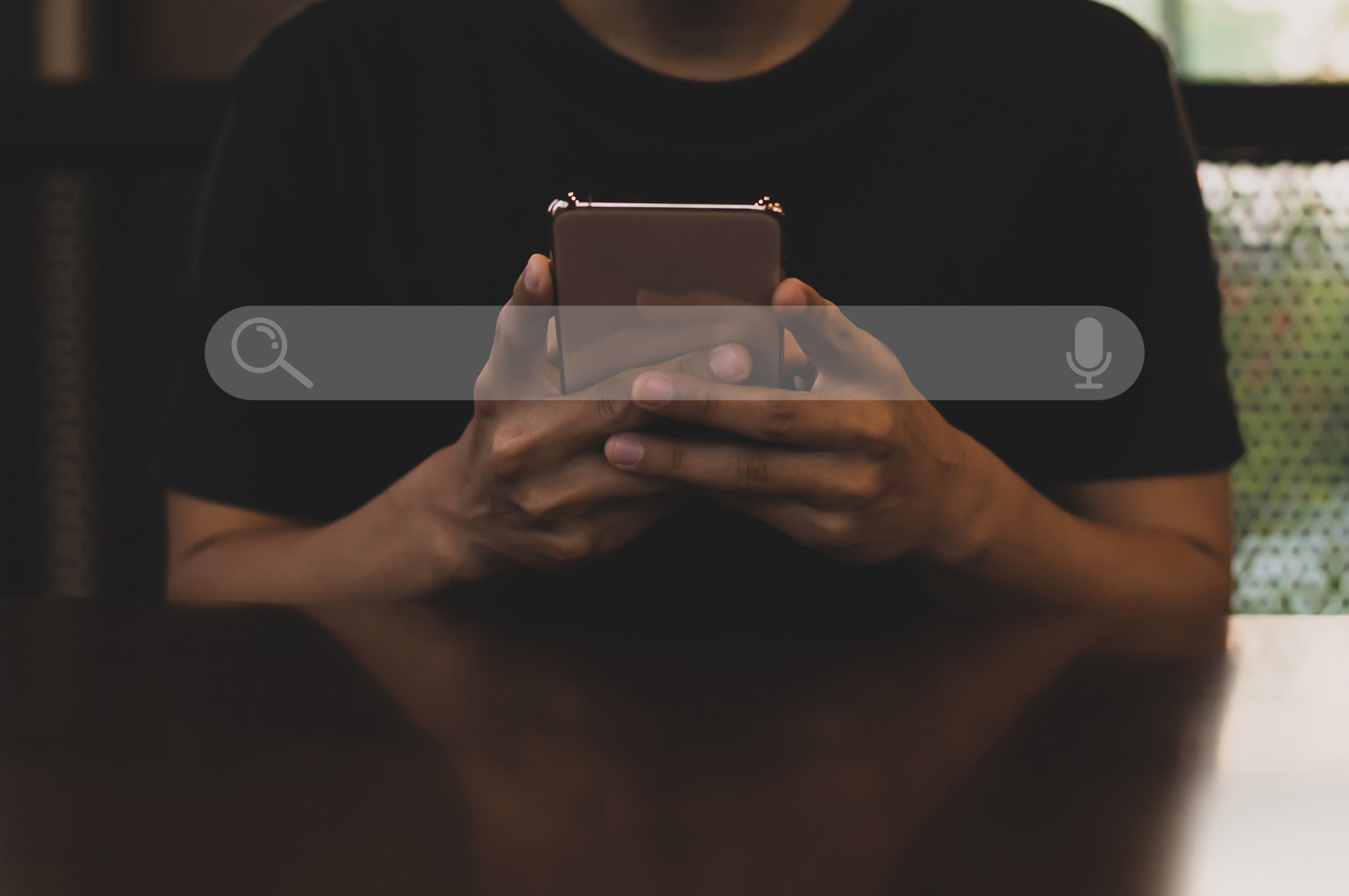 A search bar superimposed over a person looking at a smartphone.