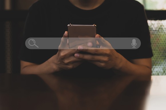 A search bar superimposed over a person looking at a smartphone.