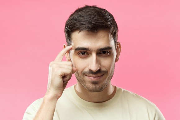 Happy person pointing at their head, indicating that they're being smart about decision making.