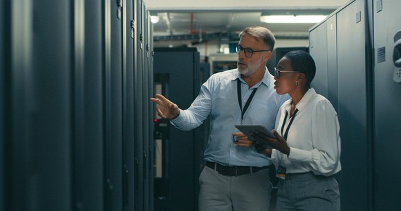 Two technicians discussing something in a data center's server room.