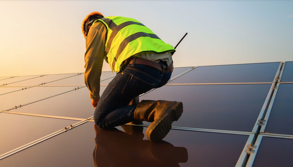 A worker installing solar microinverters on a roof.