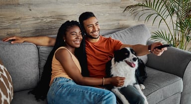 couple with dog watching TV remote