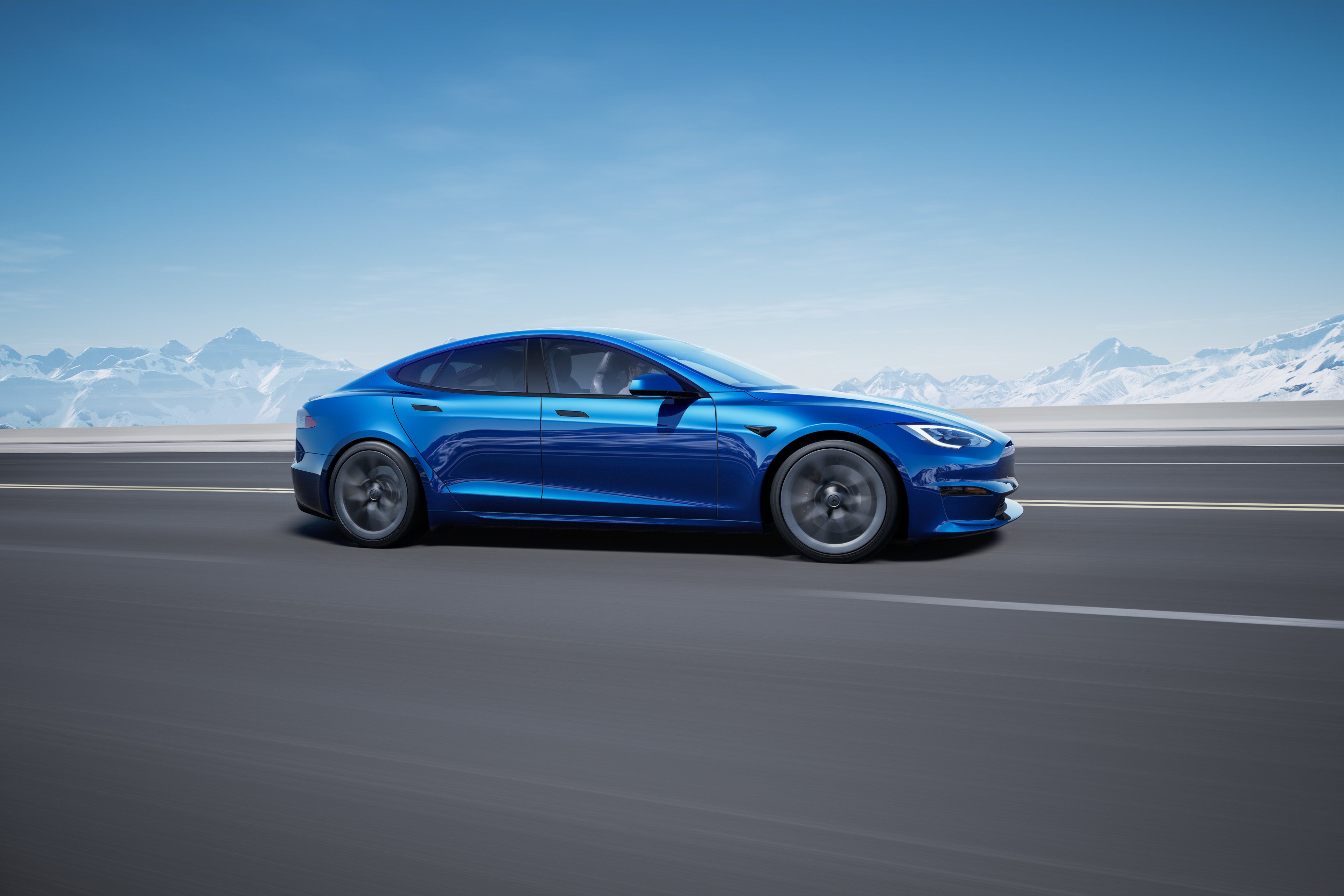 Blue Tesla Model S driving on a highway with a mountain view.