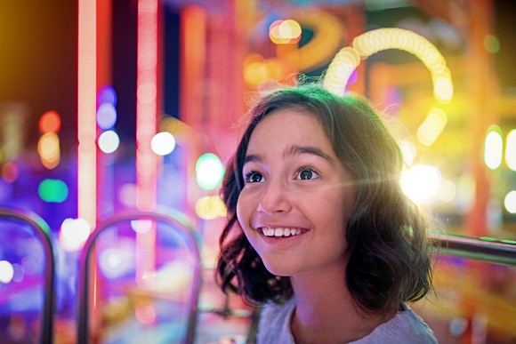 Smiling child amid glowing lights.