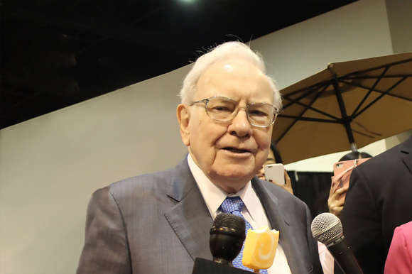 Warren Buffett standing in front of microphones.