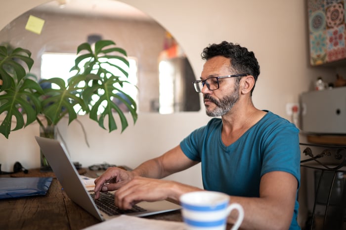 Person with a serious expression looking at a laptop.