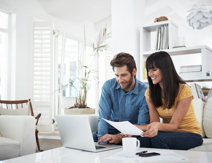 Two people discussing finances in front of laptop computer.