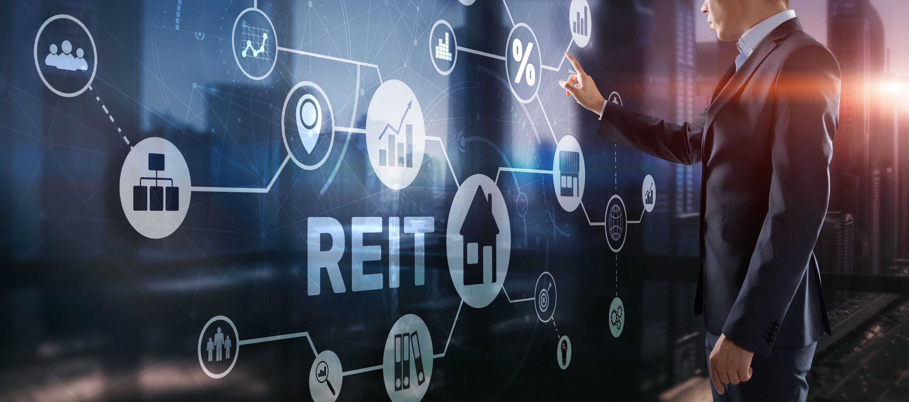 A person in a suit pointing at a digital sign that says REIT.