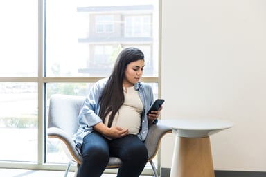pregnant person in doctor's office on smartphone
