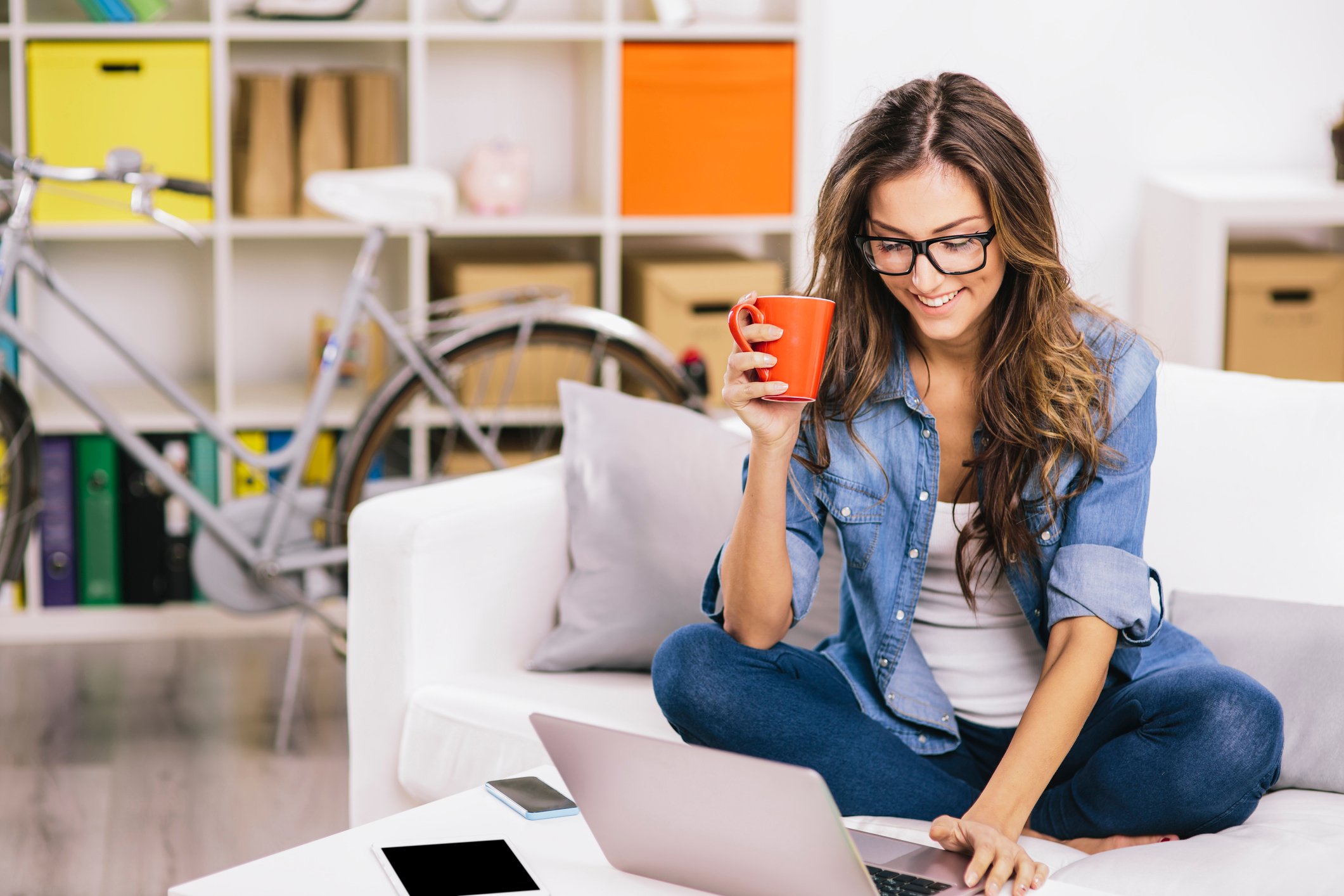 A person uses a laptop computer while drinking a coffee at home.