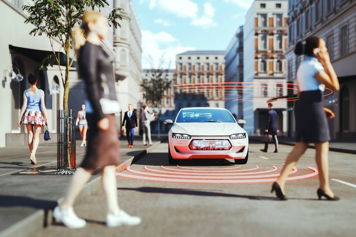 A rendering of an autonomous vehicle evaluating its surroundings on a busy street. 