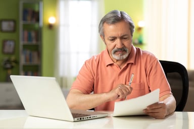 Mature person holding pen and looking at document