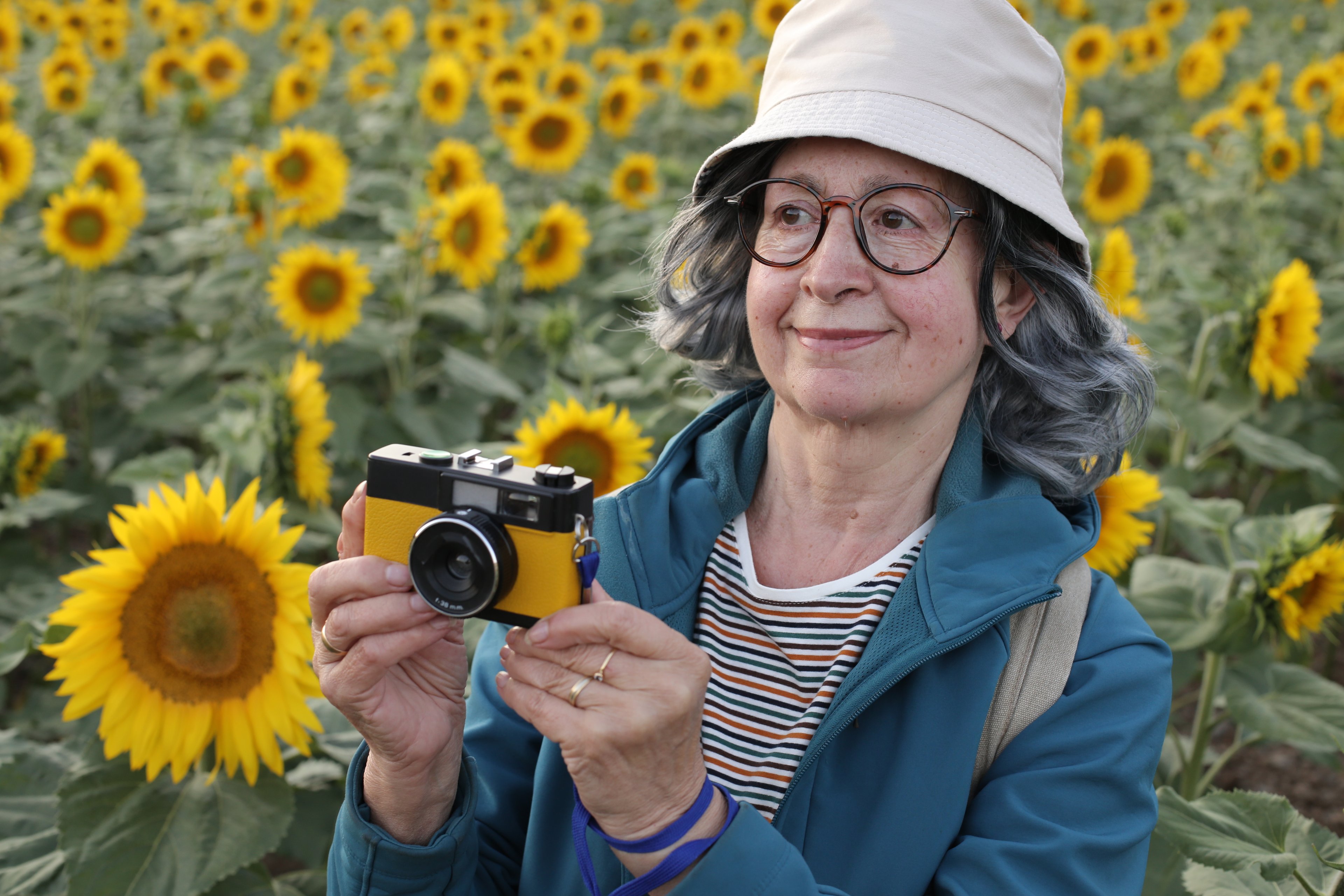 Someone holding a camera with sunflowers in the background.