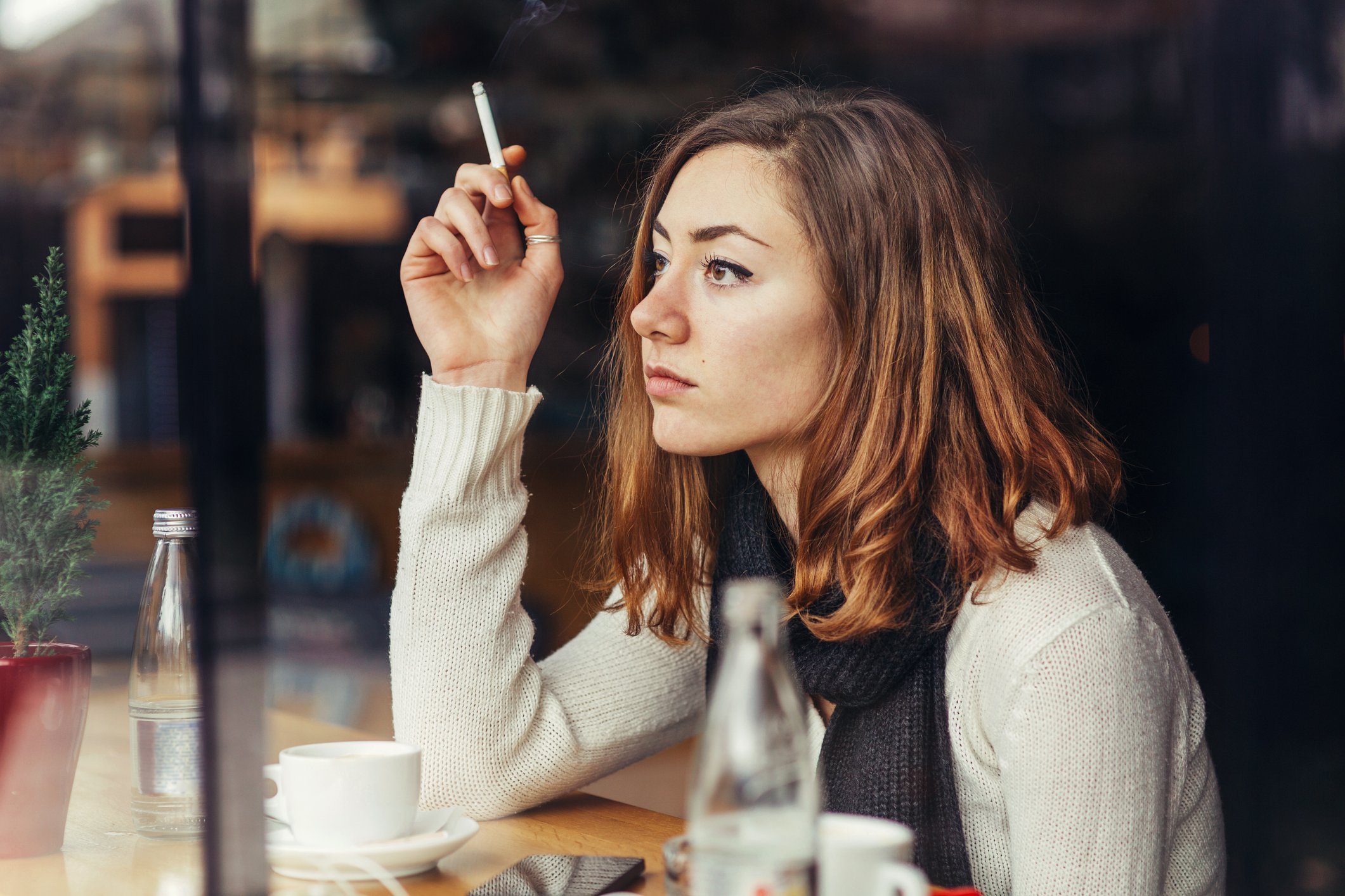 A person smokes a cigarette at a cafe