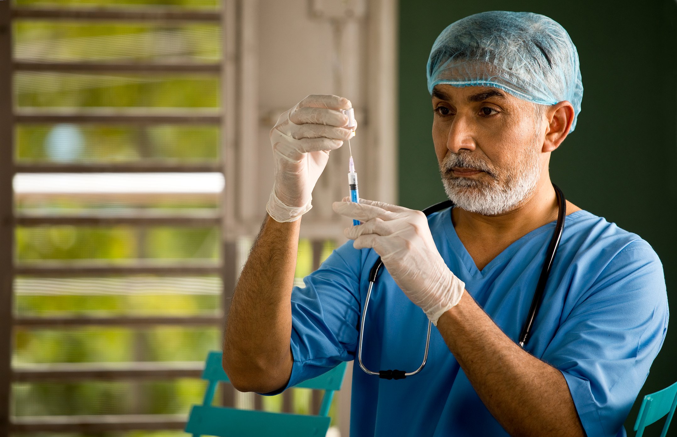 A healthcare worker loads a vaccine into a syringe from a vial.