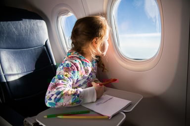Child drawing picture with crayons in airplane