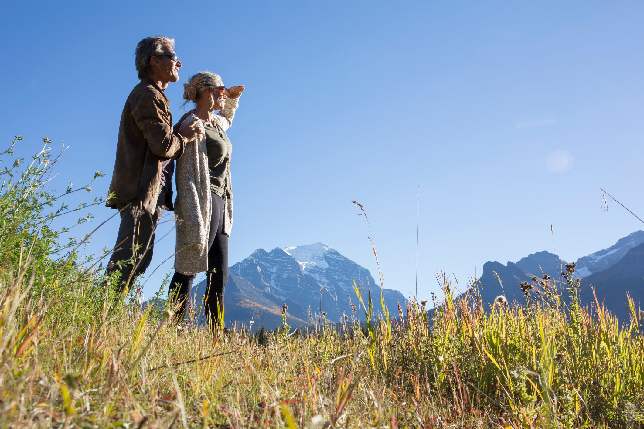 Two people outdoors, looking out at mountains in the distance.