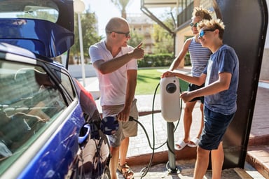 Family charges an electric vehicle in a garage.