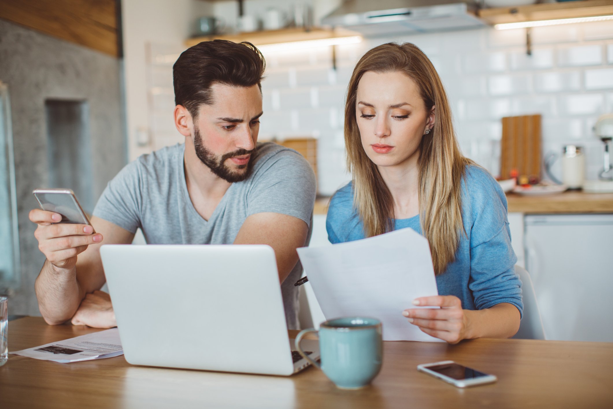 Young couple looking at finances in kitchen. 