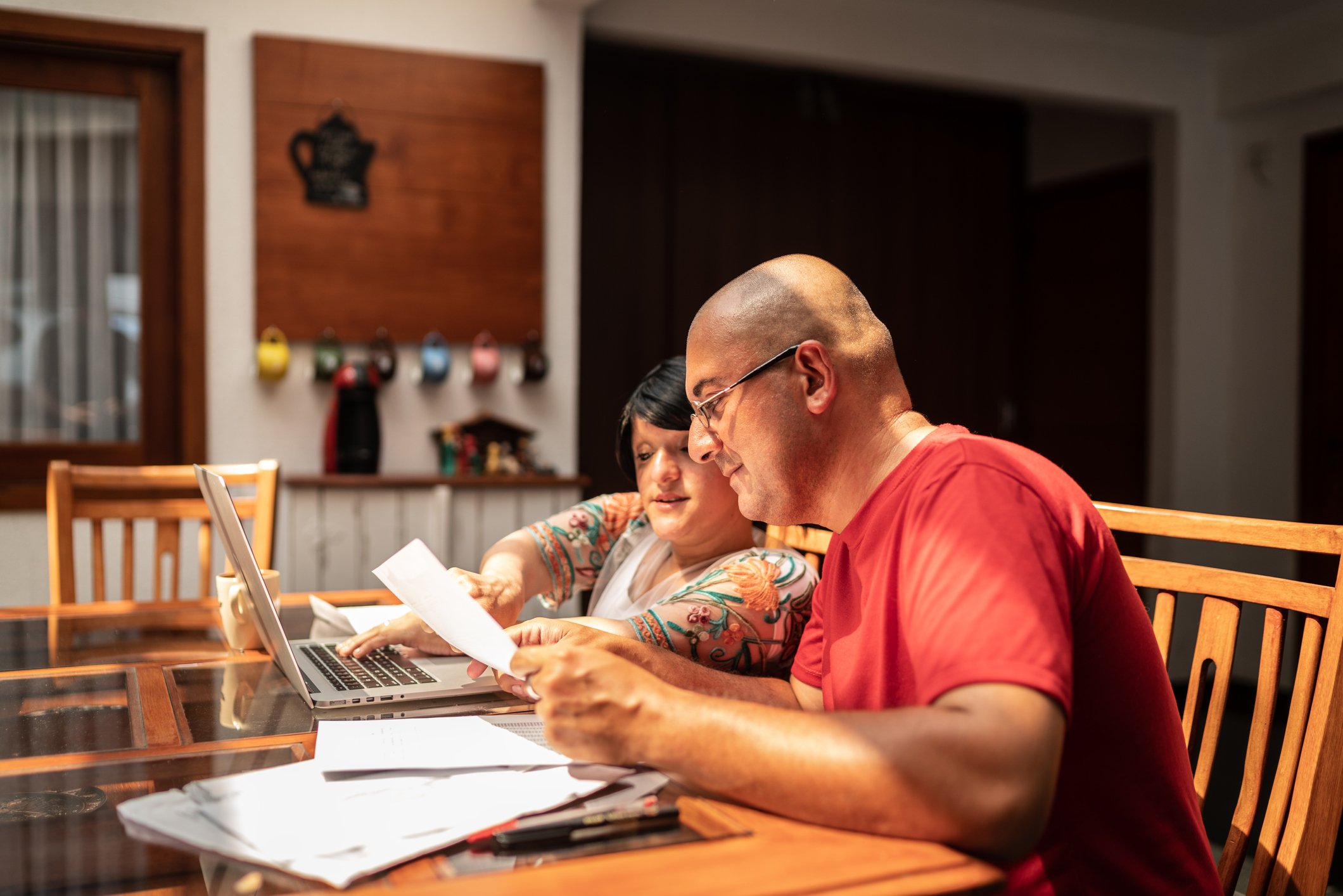 Two adults sitting at a table and looking at financial paperwork. 