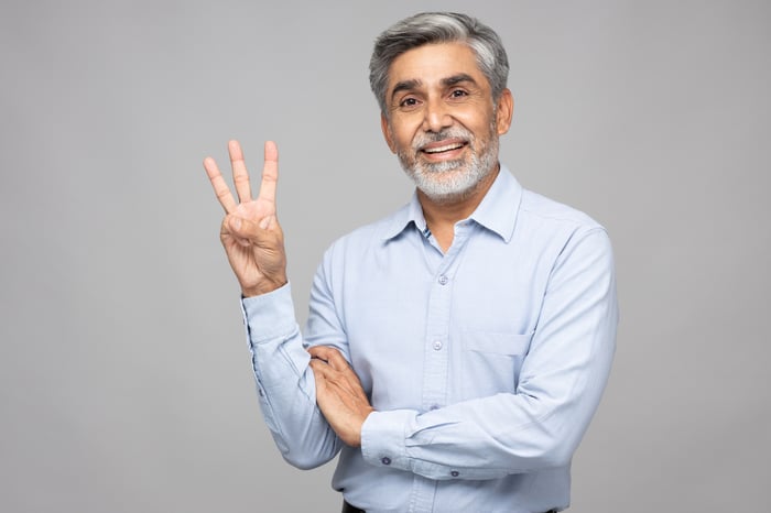 Someone is holding up three fingers and smiling. 